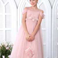 A teenage girl in a pink floral dress with a sweetheart neckline, standing in a room with a white arched door in the background.