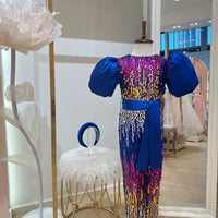 A pink and blue deni romper with gold accents and embroidery, displayed on a mannequin in a store setting.