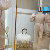 A young girl's dress and accessories displayed on a mannequin, featuring gold accents and embroidery.