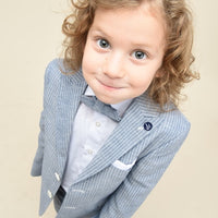 A young boy wearing a blue striped suit with a white shirt and tie, looking up at the camera.