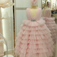 A mannequin wearing a pink, tiered dress and a floral hair accessory.