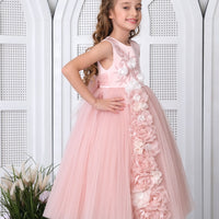 A young girl standing on a platform wearing a pink floral dress with a flowy skirt, paired with white shoes and a flower crown.