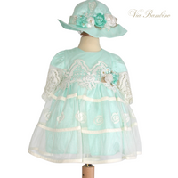 A flowy, light green baby girl's dress with intricate lace detailing, displayed on a mannequin.