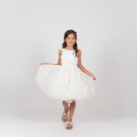 A young girl wearing a white sleeveless knee-length dress with ruffle detailing and a full skirt, standing against a plain background.