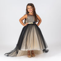 A girl wearing a sleeveless floor-length dress with a sheer bodice covered in lace, and sequins, in black and white color.