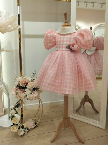 A pink checkered girls' dress with short puffed sleeves and a knee-length skirt displayed on a mannequin.